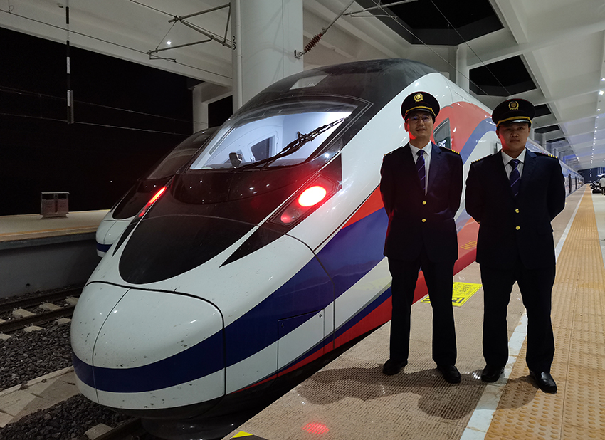 劉銀能（右一）與中國師父鄔俊鴻在動車組前合影。受訪者供圖