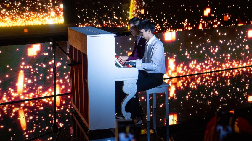 智能仿生手使用者古月與少年鋼琴家舒海峰合奏。主辦方供圖